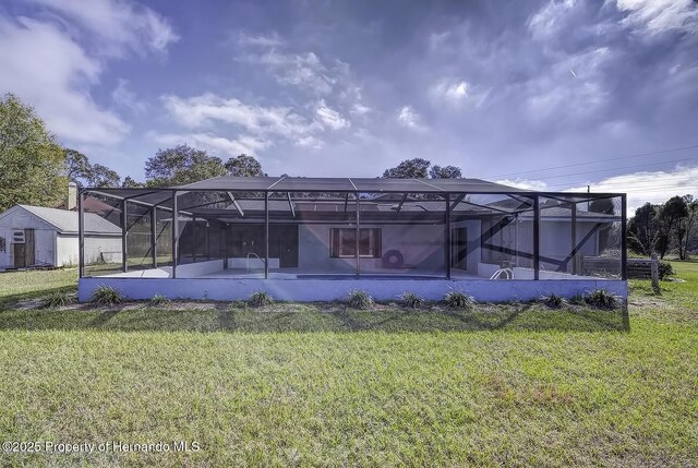 rear view of house with a yard, glass enclosure, and a patio