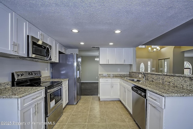 kitchen with appliances with stainless steel finishes, a sink, recessed lighting, white cabinetry, and a textured ceiling