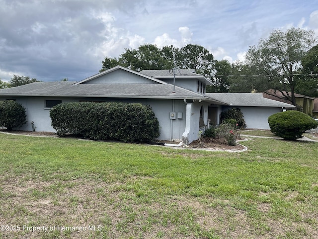 view of front of house featuring stucco siding, a front yard, and roof with shingles