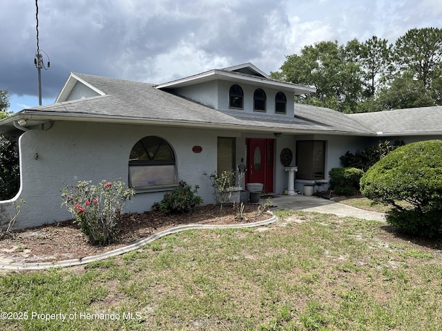 view of front of property featuring stucco siding, roof with shingles, and a front lawn