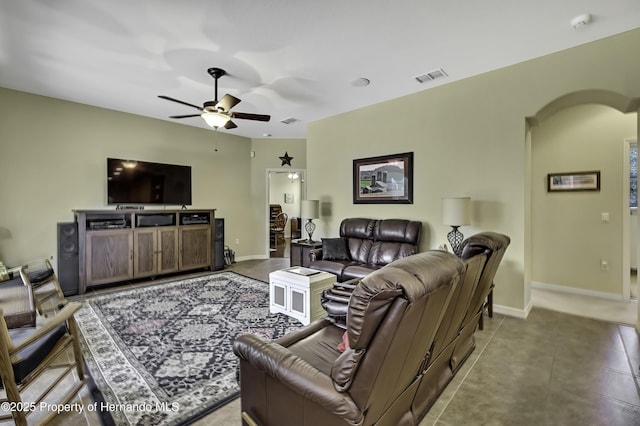 living area with ceiling fan, baseboards, and arched walkways