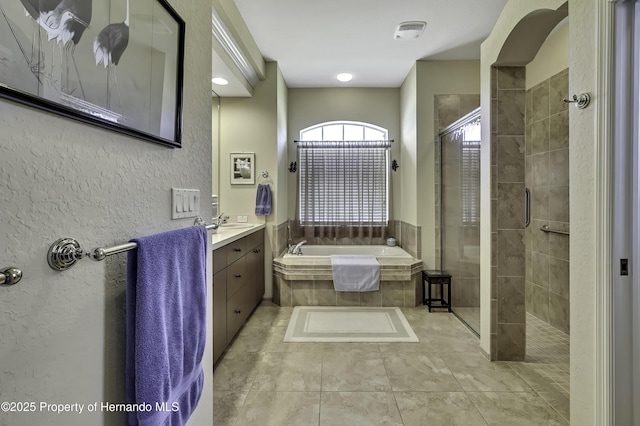 bathroom featuring a stall shower, a garden tub, and vanity