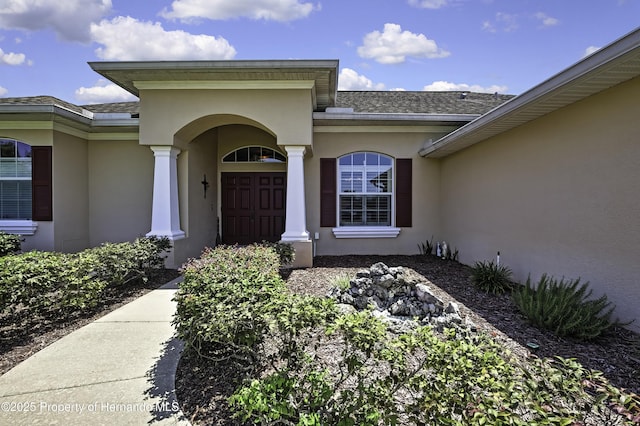 property entrance featuring stucco siding and roof with shingles