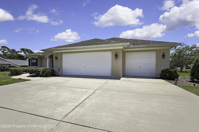 view of front facade featuring concrete driveway, stucco siding, and a garage