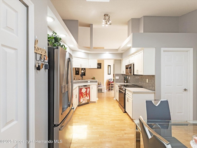 11350 Copley Ct, Spring Hill, FL 34609 - kitchen featuring appliances with stainless steel finishes, light countertops, light wood finished floors, white cabinets, and backsplash