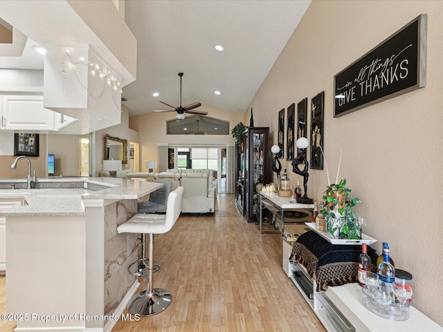 11350 Copley Ct, Spring Hill, FL 34609 - kitchen with light wood-style flooring, a ceiling fan, light stone countertops, white cabinetry, and high vaulted ceiling