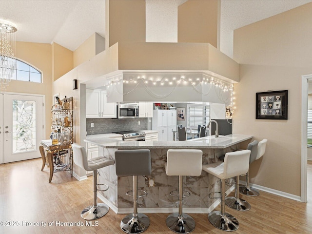 11350 Copley Ct, Spring Hill, FL 34609 - kitchen with stainless steel appliances, high vaulted ceiling, a kitchen bar, a peninsula, and light wood-style flooring