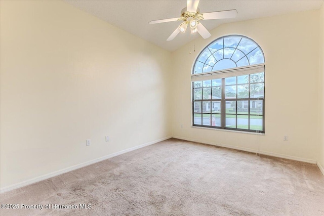 carpeted spare room featuring vaulted ceiling, ceiling fan, and baseboards