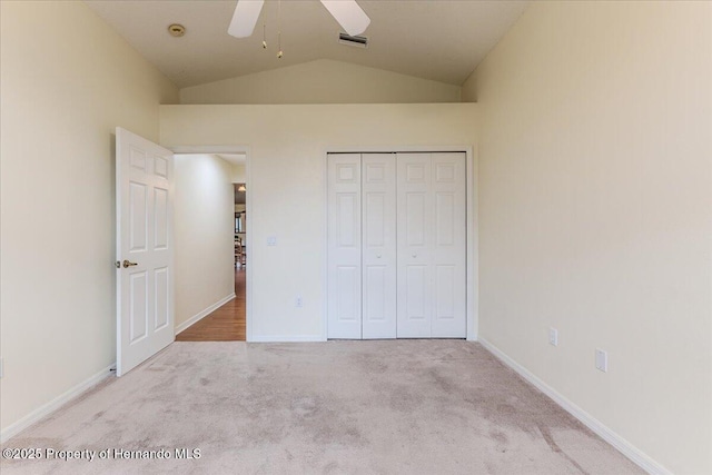 unfurnished bedroom featuring carpet floors, lofted ceiling, a closet, baseboards, and a ceiling fan