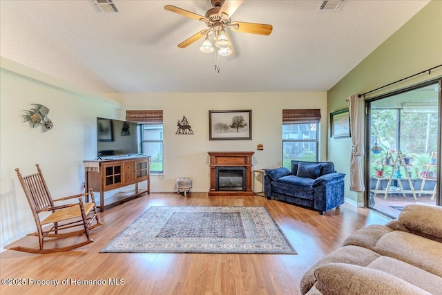 living room featuring a glass covered fireplace, wood finished floors, ceiling fan, and baseboards