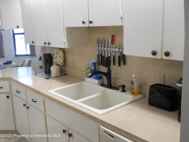 kitchen with white cabinets, a sink, light countertops, and backsplash