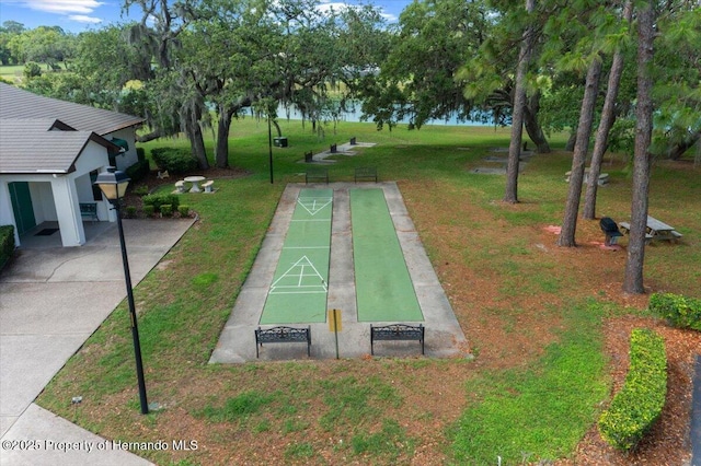 view of community with shuffleboard and a yard