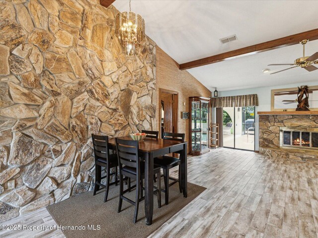 8393 Delaware Dr, Weeki Wachee, FL 34607 - dining space with wood finished floors, ceiling fan, a stone fireplace, and a chandelier