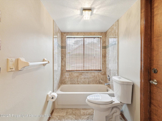 8393 Delaware Dr, Weeki Wachee, FL 34607 - full bath featuring toilet, baseboards, shower / bathtub combination, a textured ceiling, and stone finish flooring