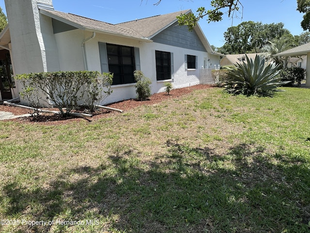 2351 Palm Springs Ct, Spring Hill, FL 34606 - view of side of property with a yard, stucco siding, a shingled roof, and a chimney