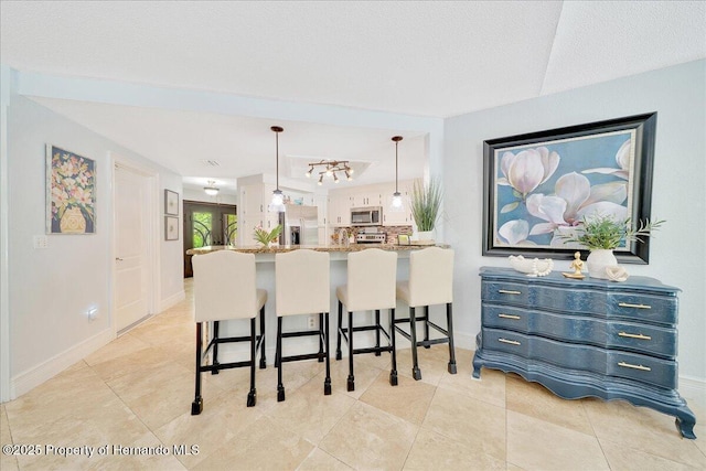 21000 Exeter Ct, Brooksville, FL 34601 - kitchen with stainless steel appliances, a breakfast bar area, baseboards, decorative light fixtures, and light tile patterned floors
