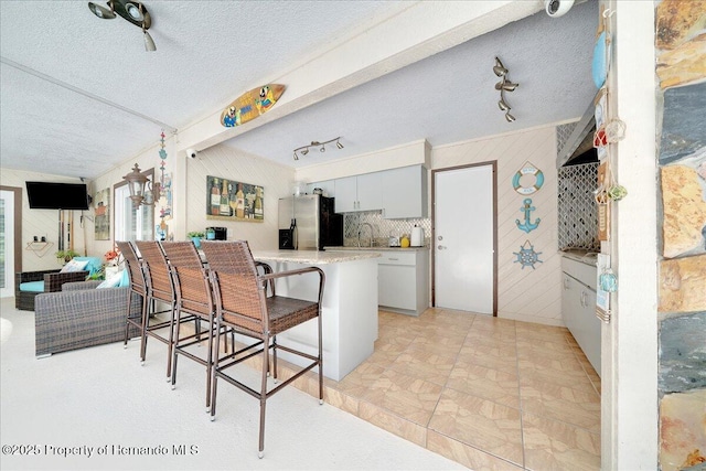 21000 Exeter Ct, Brooksville, FL 34601 - kitchen featuring stainless steel fridge, a kitchen breakfast bar, a peninsula, a textured ceiling, and light countertops