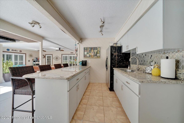 21000 Exeter Ct, Brooksville, FL 34601 - kitchen featuring a peninsula, a kitchen breakfast bar, a sink, white cabinetry, and light stone counters