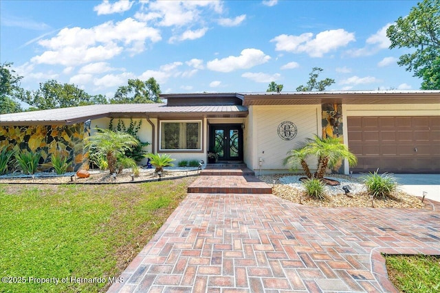 21000 Exeter Ct, Brooksville, FL 34601 - mid-century modern home featuring french doors, an attached garage, metal roof, a front yard, and concrete driveway