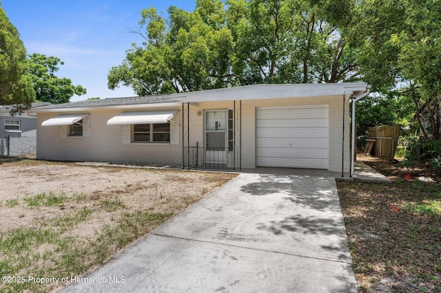 ranch-style home featuring brick siding, fence, concrete driveway, and a garage