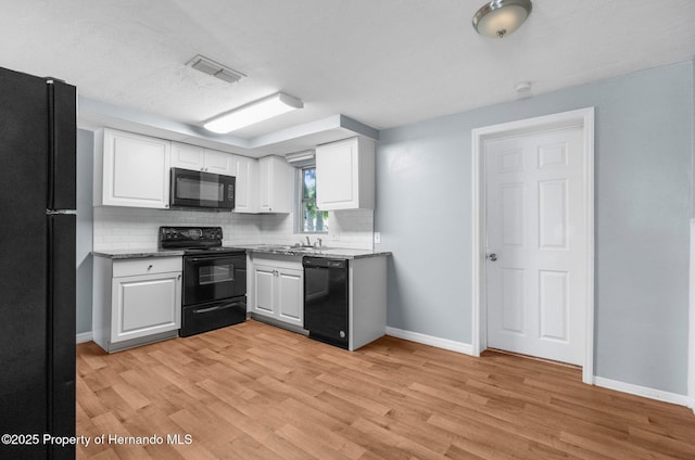 kitchen with black appliances, decorative backsplash, white cabinets, and light wood-type flooring