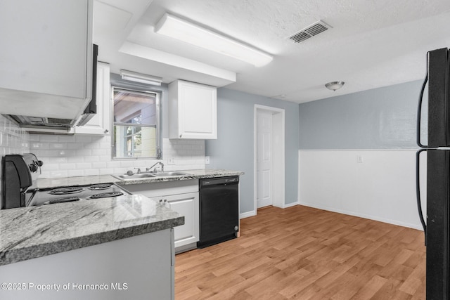 kitchen featuring black appliances, a sink, white cabinets, tasteful backsplash, and light wood-type flooring