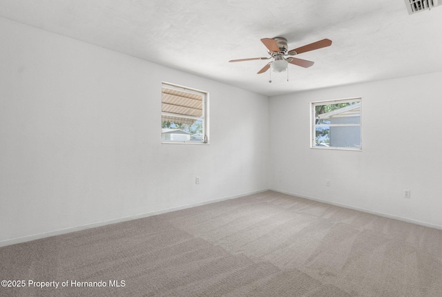empty room featuring plenty of natural light, ceiling fan, light colored carpet, and baseboards