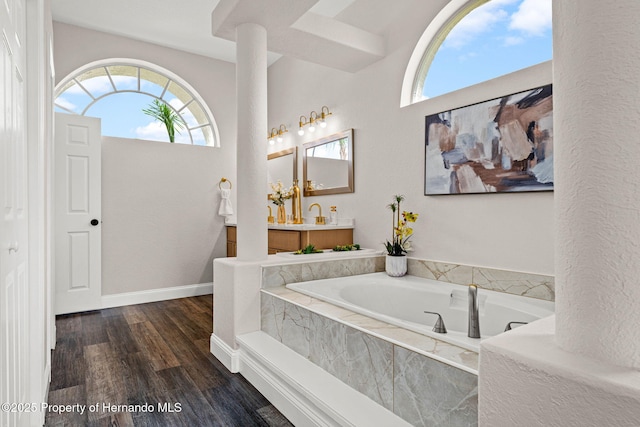 full bathroom with a bath, wood finished floors, vanity, and baseboards