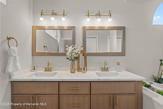 bathroom with double vanity and a textured wall