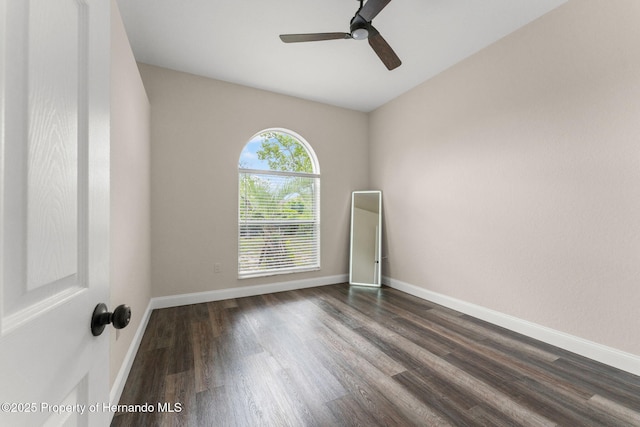 empty room featuring a ceiling fan, dark wood finished floors, and baseboards