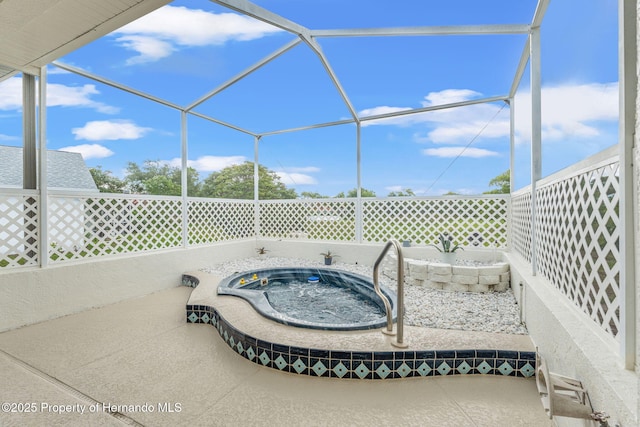 view of patio / terrace featuring an outdoor hot tub and glass enclosure