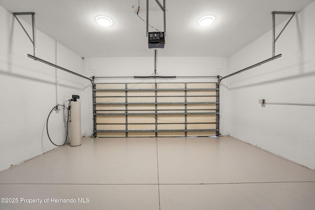 garage with concrete block wall and a garage door opener