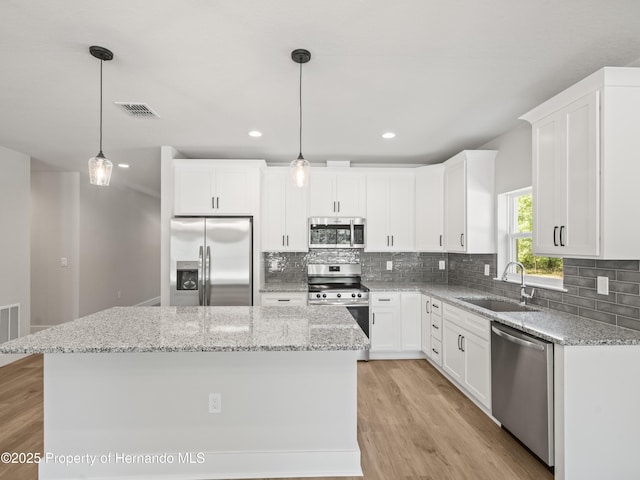 14353 Chimney Swift Rd, Weeki Wachee, FL 34614 - kitchen featuring stainless steel appliances, a sink, a center island, decorative backsplash, and white cabinets