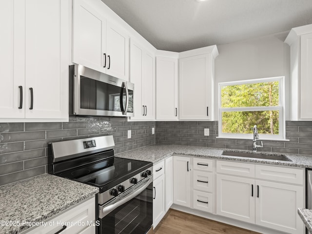 14353 Chimney Swift Rd, Weeki Wachee, FL 34614 - kitchen with appliances with stainless steel finishes, a sink, white cabinetry, and light stone countertops