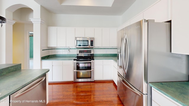 4048 St Ives Blvd, Spring Hill, FL 34609 - kitchen with stainless steel appliances, backsplash, dark wood-type flooring, white cabinets, and decorative columns