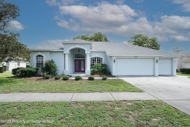 4048 St Ives Blvd, Spring Hill, FL 34609 - view of front of home featuring french doors, a garage, concrete driveway, and stucco siding