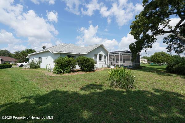 4048 St Ives Blvd, Spring Hill, FL 34609 - back of house featuring a lawn and glass enclosure