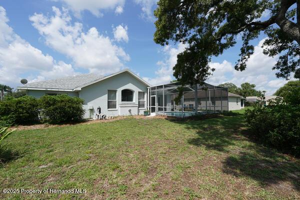 4048 St Ives Blvd, Spring Hill, FL 34609 - rear view of house with a yard and glass enclosure