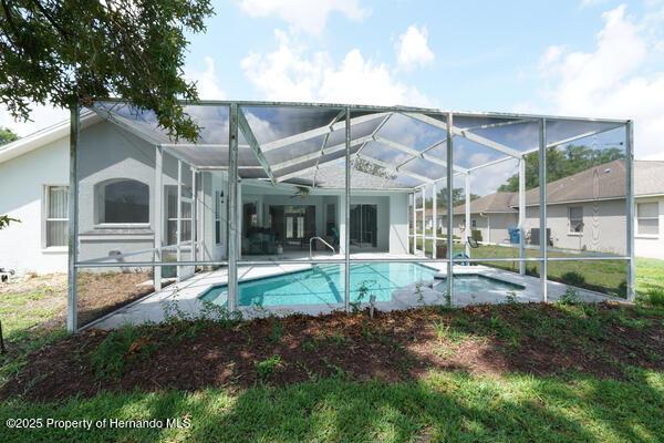 4048 St Ives Blvd, Spring Hill, FL 34609 - rear view of house with an outdoor pool, a patio area, and glass enclosure