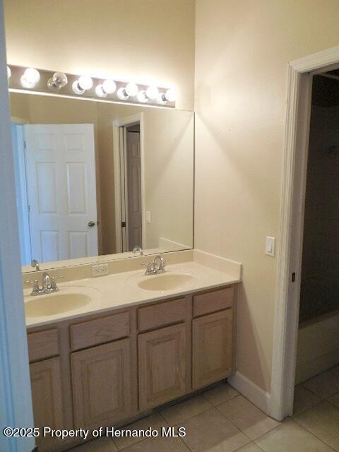 bathroom featuring tile patterned floors, double vanity, and baseboards