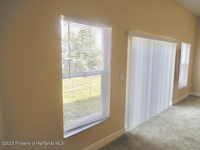 carpeted empty room featuring baseboards