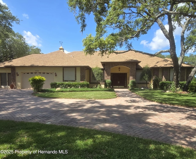 10430 Ramble Ridge Ct, Weeki Wachee, FL 34613 - view of front of home featuring a garage, a front yard, stucco siding, and decorative driveway