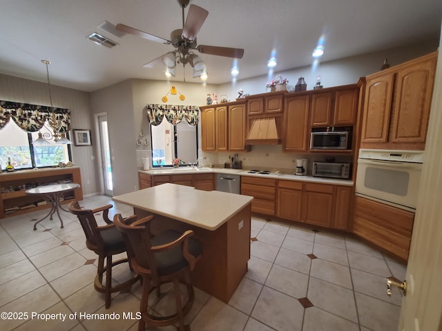 10430 Ramble Ridge Ct, Weeki Wachee, FL 34613 - kitchen featuring stainless steel appliances, light countertops, premium range hood, ceiling fan, and a center island