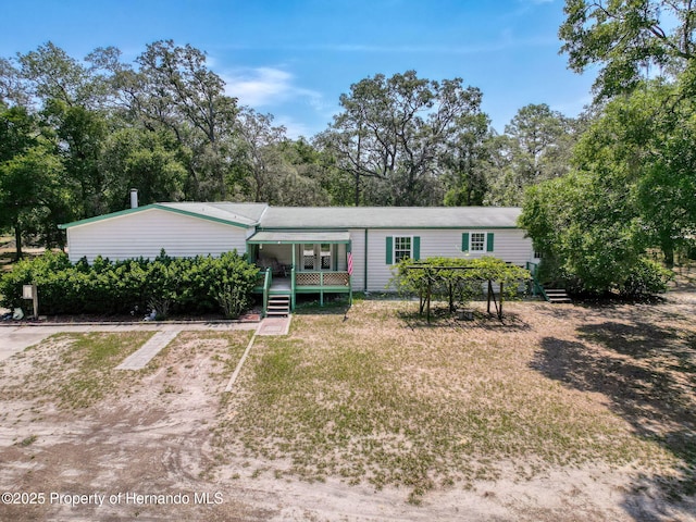 16173 Wiscon Rd, Brooksville, FL 34601 - view of front of property featuring a front lawn, dirt driveway, and view of wooded area