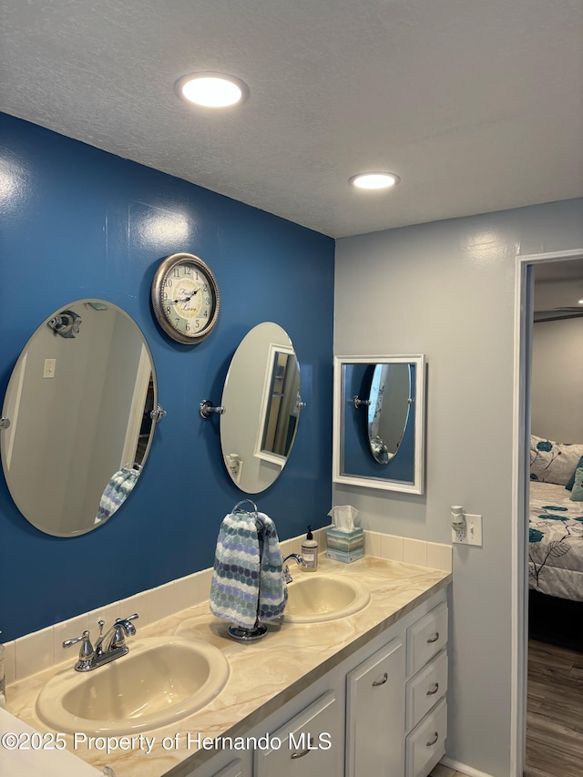15693 Brookridge Blvd, Brooksville, FL 34613 - ensuite bathroom with double vanity, wood finished floors, a textured ceiling, and recessed lighting