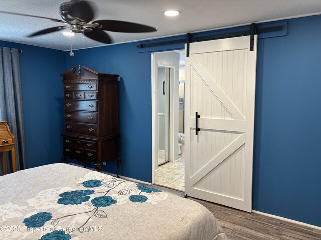 15693 Brookridge Blvd, Brooksville, FL 34613 - bedroom featuring a barn door, wood finished floors, and ceiling fan