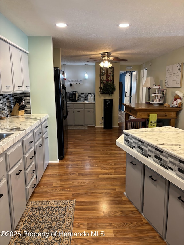 15693 Brookridge Blvd, Brooksville, FL 34613 - kitchen with black fridge with ice dispenser, wood finished floors, ceiling fan, decorative backsplash, and recessed lighting