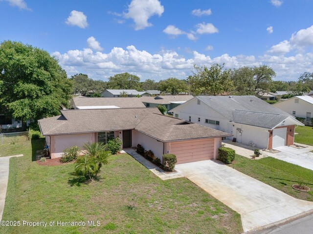 10820 Hachita Dr, Port Richey, FL 34668 - view of front of home with an attached garage, concrete driveway, a front lawn, and a shingled roof