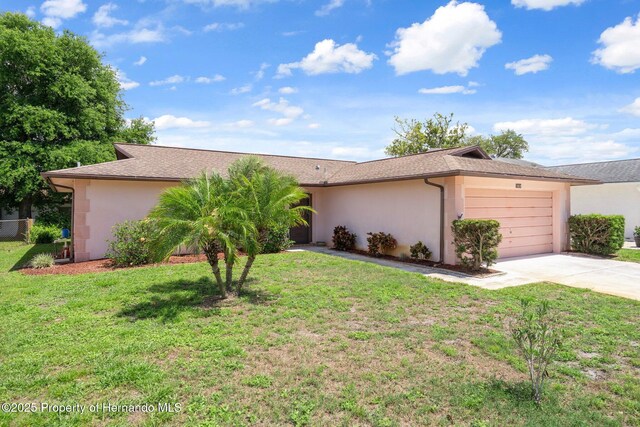 10820 Hachita Dr, Port Richey, FL 34668 - view of front of home with stucco siding, driveway, an attached garage, a front lawn, and roof with shingles