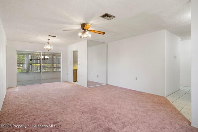 10820 Hachita Dr, Port Richey, FL 34668 - carpeted spare room featuring a ceiling fan, a chandelier, a textured ceiling, and tile patterned floors